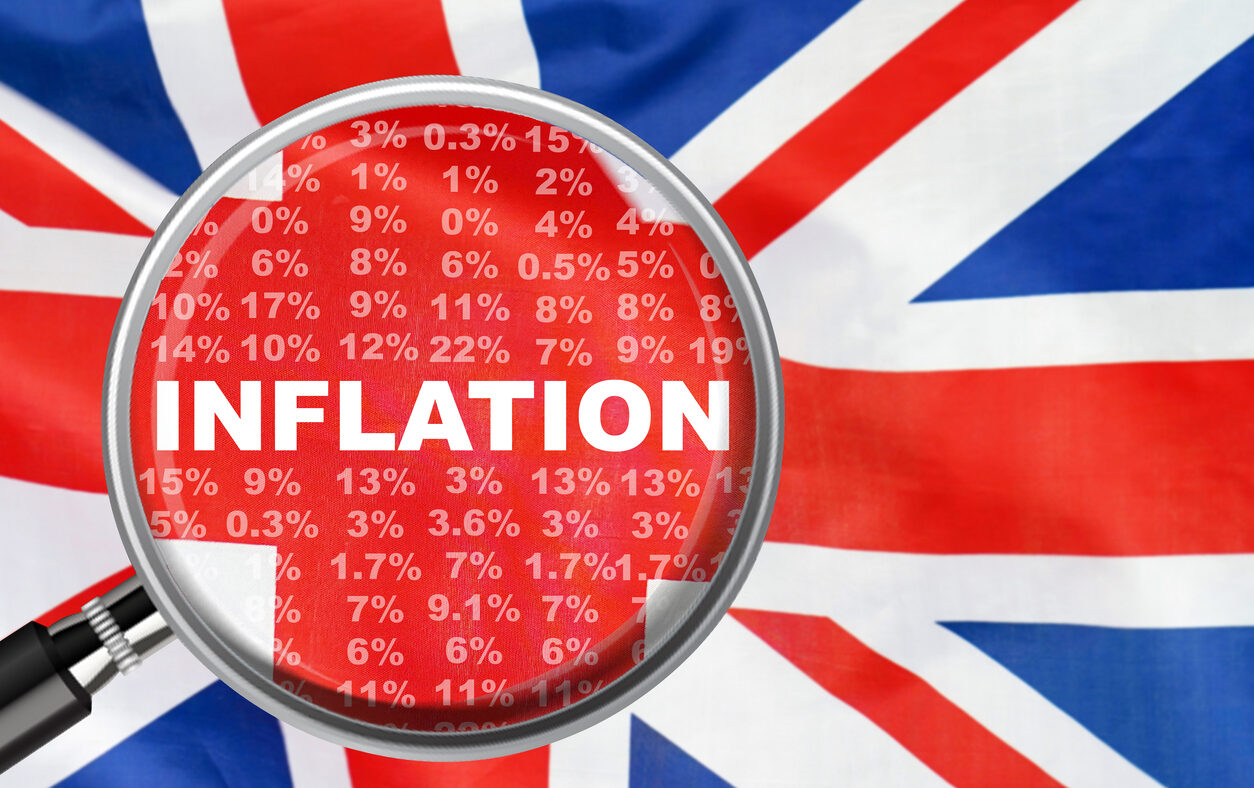 Magnifying glass focused on the word inflation on UK flag background. Hike interest rate. Inflation income crisis. Inflation, tax, cash flow and another financial concept in Britannia