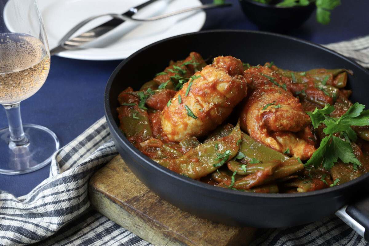 Chicken with snow peas and tomato sauce in a frying pan. Homemade cooking. Overhead view.