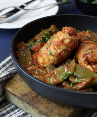 Chicken with snow peas and tomato sauce in a frying pan. Homemade cooking. Overhead view.