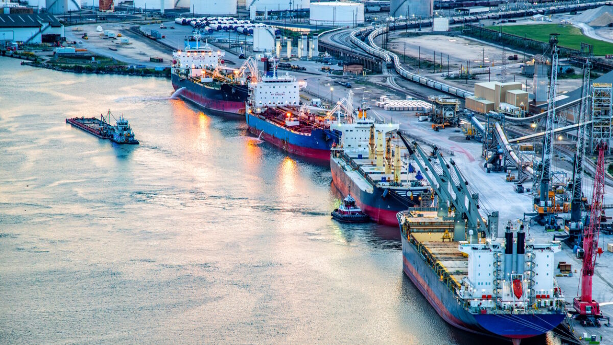 A variety of ships including a large bulk carrier and liquid tanker ships along the Houston Ship Channel about four miles from downtown Houston, Texas shot via helicopter from an altitude of about 400 feet over the river