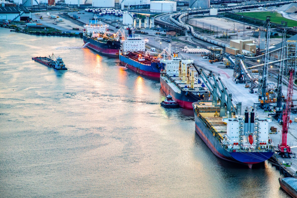 A variety of ships including a large bulk carrier and liquid tanker ships along the Houston Ship Channel about four miles from downtown Houston, Texas shot via helicopter from an altitude of about 400 feet over the river
