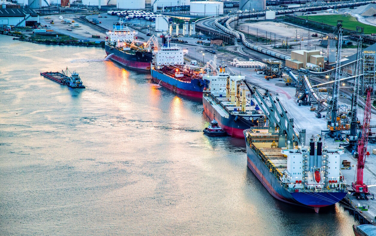 A variety of ships including a large bulk carrier and liquid tanker ships along the Houston Ship Channel about four miles from downtown Houston, Texas shot via helicopter from an altitude of about 400 feet over the river