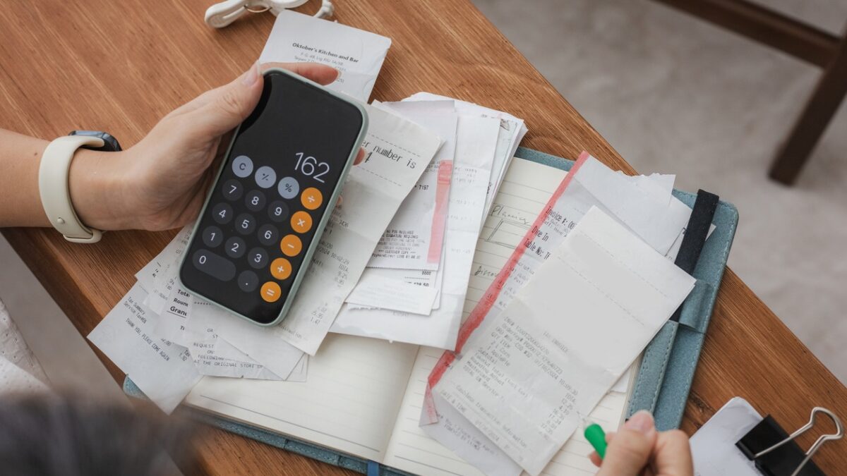 Close up a woman managing her home finances with a smartphone, she reviews financial bills. Concepts include financial planning, taxes, spending, budgeting, and financial challenges.