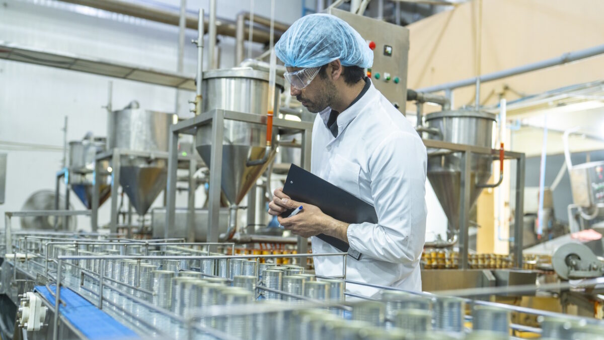 Professional closely examining production materials on a conveyor system, representing dedication to quality, precision, and modern technology in manufacturing processes.