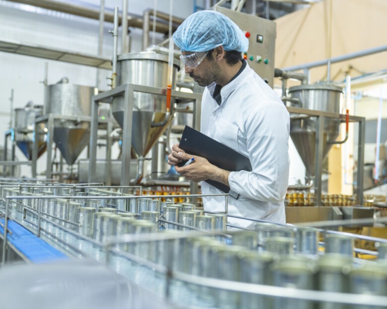 Professional closely examining production materials on a conveyor system, representing dedication to quality, precision, and modern technology in manufacturing processes.