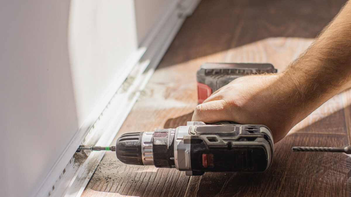Installing baseboards. Drilling hole in wall