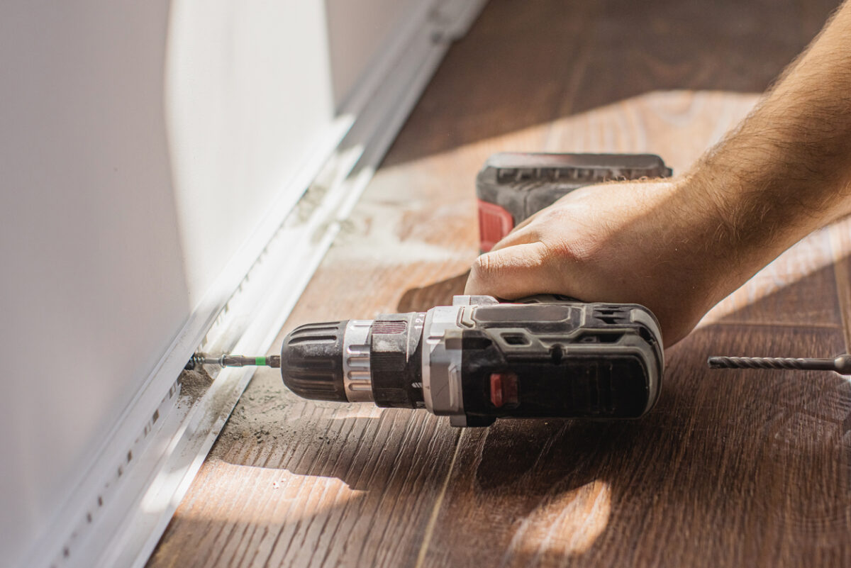 Installing baseboards. Drilling hole in wall