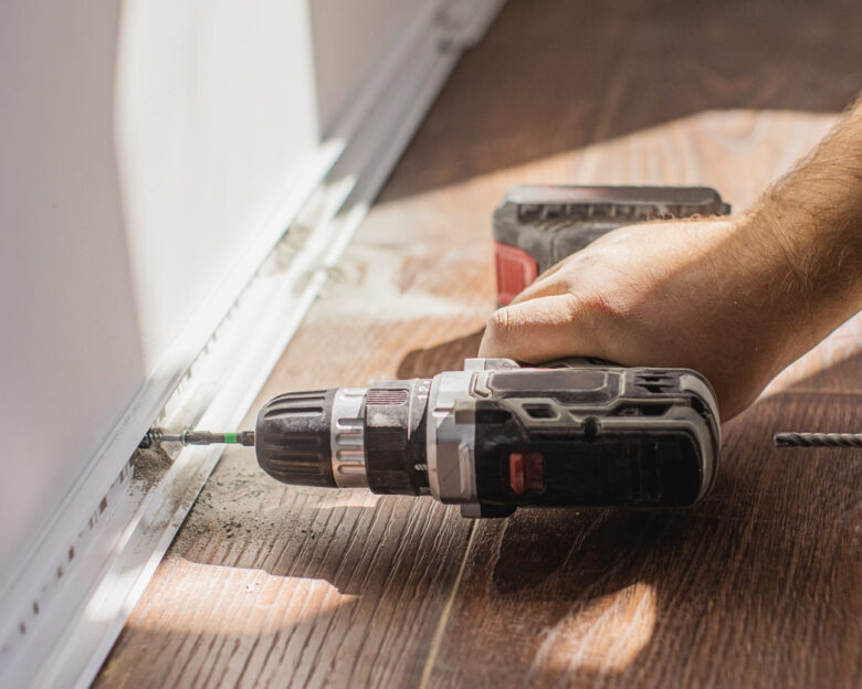 Installing baseboards. Drilling hole in wall