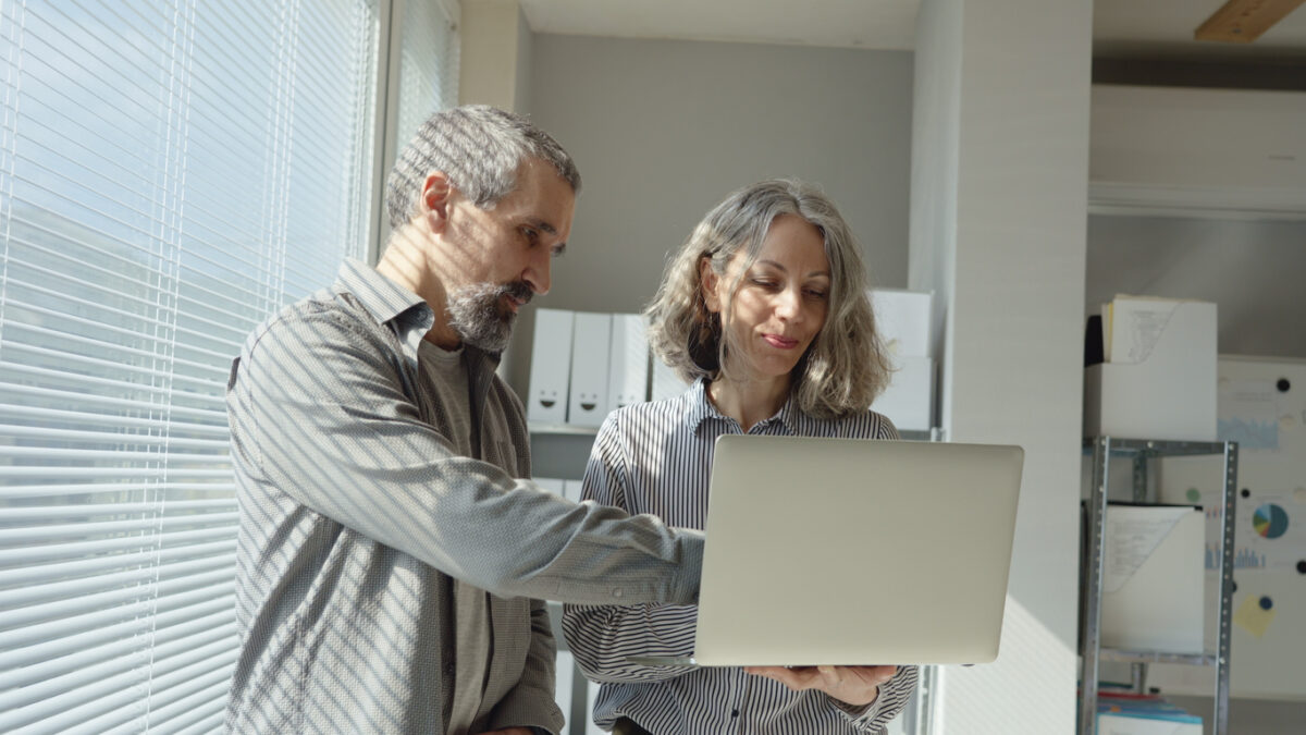 Team of mature business woman collaborating with colleague on project development in modern office using artificial intelligence. Investments, financial management & expertise