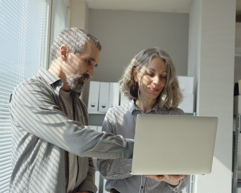 Team of mature business woman collaborating with colleague on project development in modern office using artificial intelligence. Investments, financial management & expertise