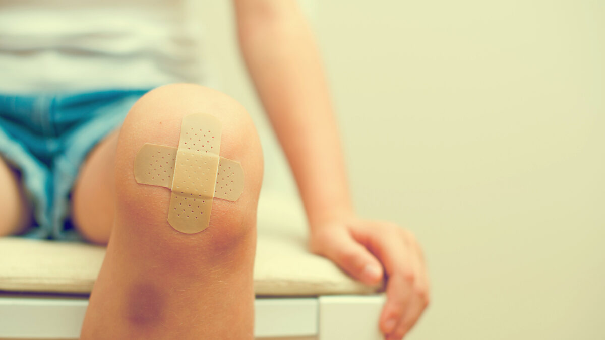 Child knee with an adhesive bandage and bruise.