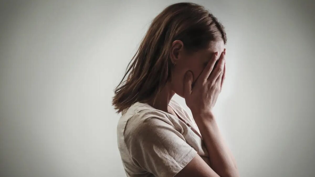 Portrait of depressed woman, covering face with her hands, side view