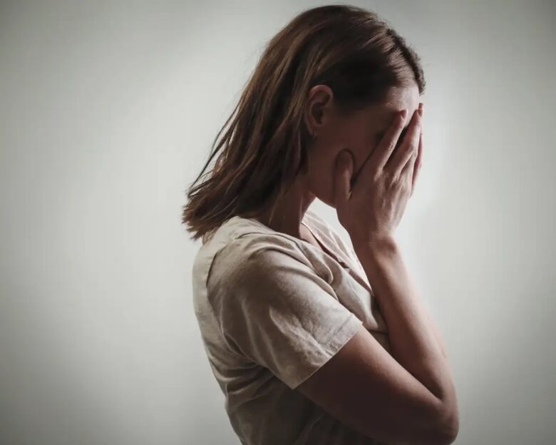 Portrait of depressed woman, covering face with her hands, side view