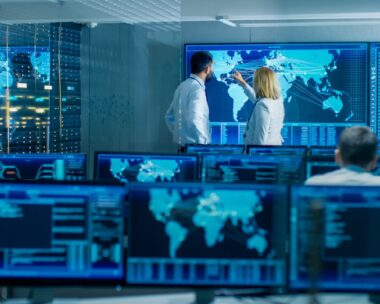 In the System Monitoring Room Two Senior Operators Work on a Big Interactive Map. Facility is Full of Screens Showing Technical Data.