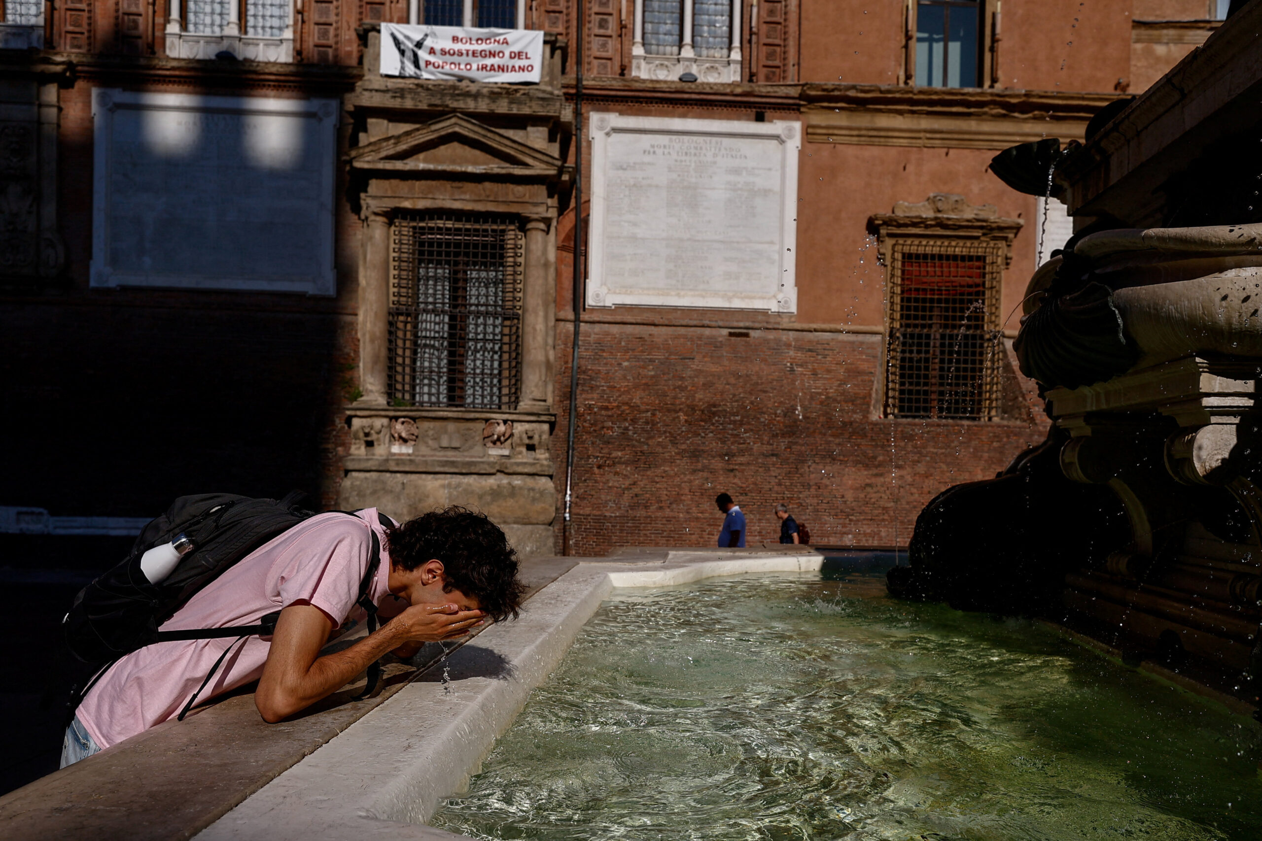 A man cools himself with water from the Fountain of Neptune during hot weather in Bologna, Italy, June 20, 2026. REUTERS/Vincenzo Livieri