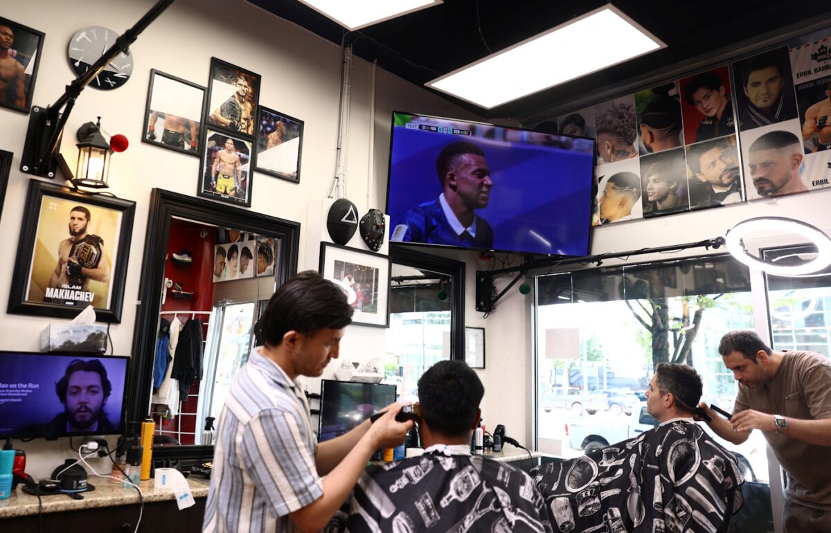 Soccer Football - FIFA World Cup 2026 - Vancouver, Canada - June 16, 2026 Customers have their hair cut at Erbil Barbers in Vancouver as the France v Senegal match is shown on the TV