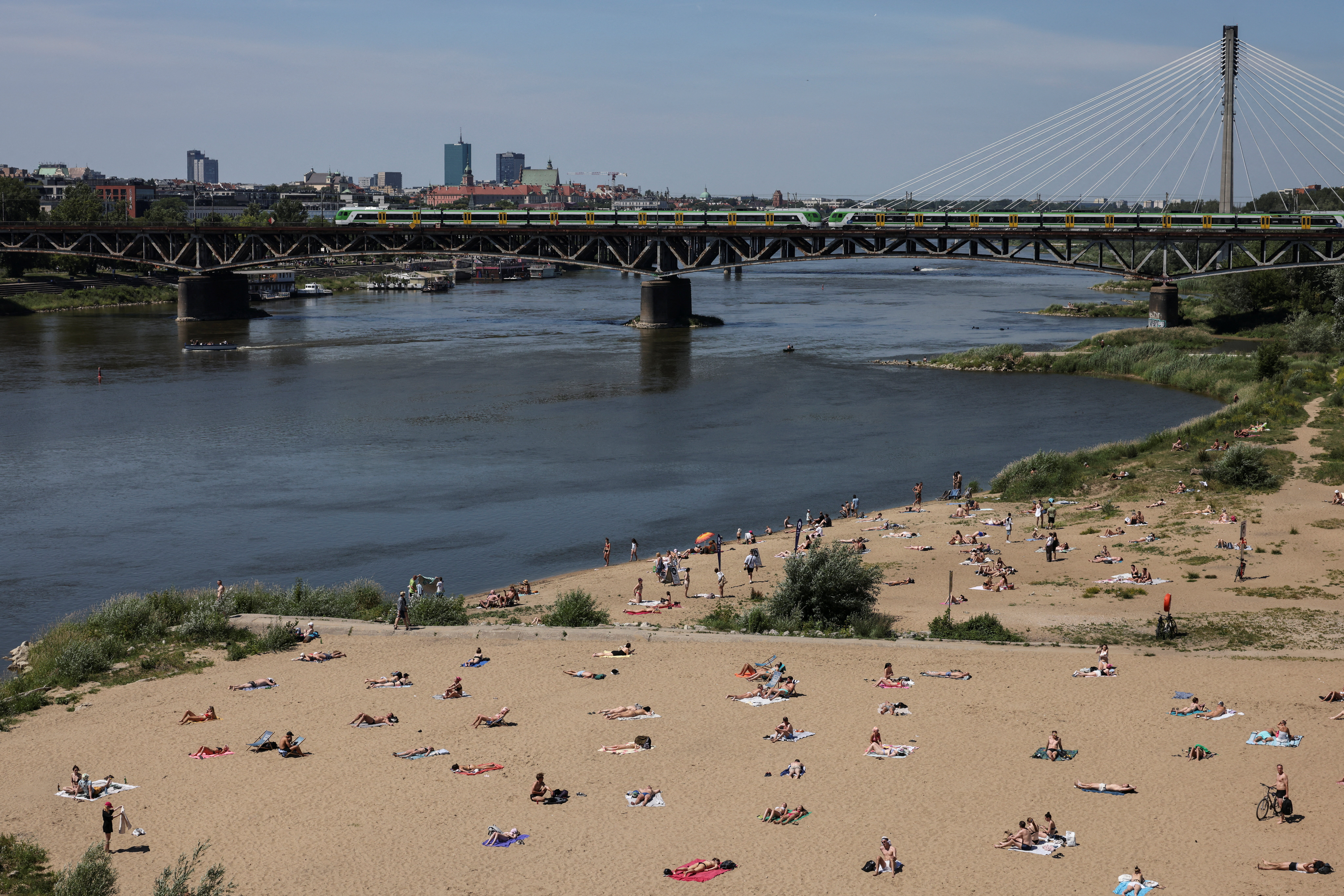 People relax on a city beach by the Vistula River in central Warsaw during first heatwave of the season, as water in the Vistula is nearing low levels, in Warsaw, Poland, June 20, 2026. REUTERS/Kuba Stezycki