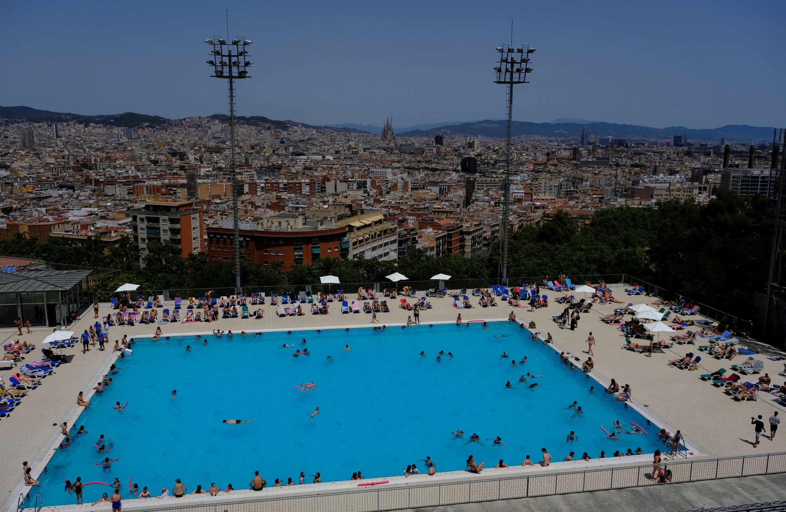 Tourists and locals enjoy a swimming pool as temperatures rise, during a heatwave affecting a large part of Spain, in Barcelona, Spain, June 21, 2026. REUTERS/Nacho Doce