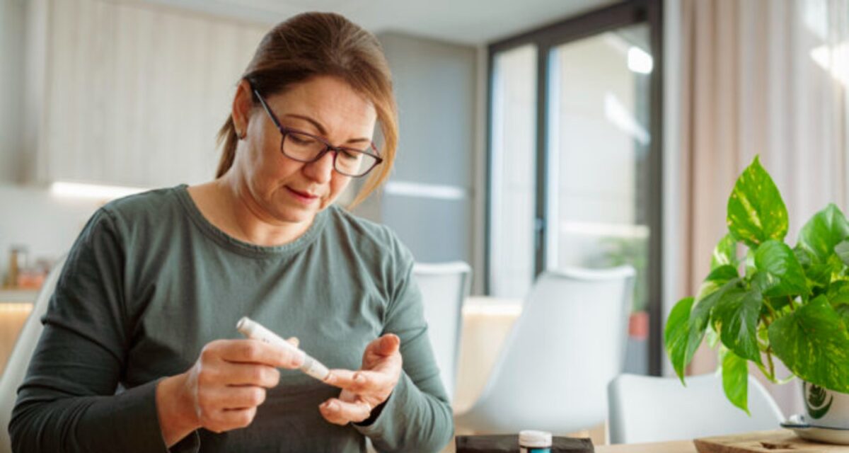 Mature diabetic woman using lancet on finger for checking blood sugar level by Glucose meter. High resolution 42Mp indoors digital capture taken with SONY A7rII and Zeiss Batis 40mm F2.0 CF lens