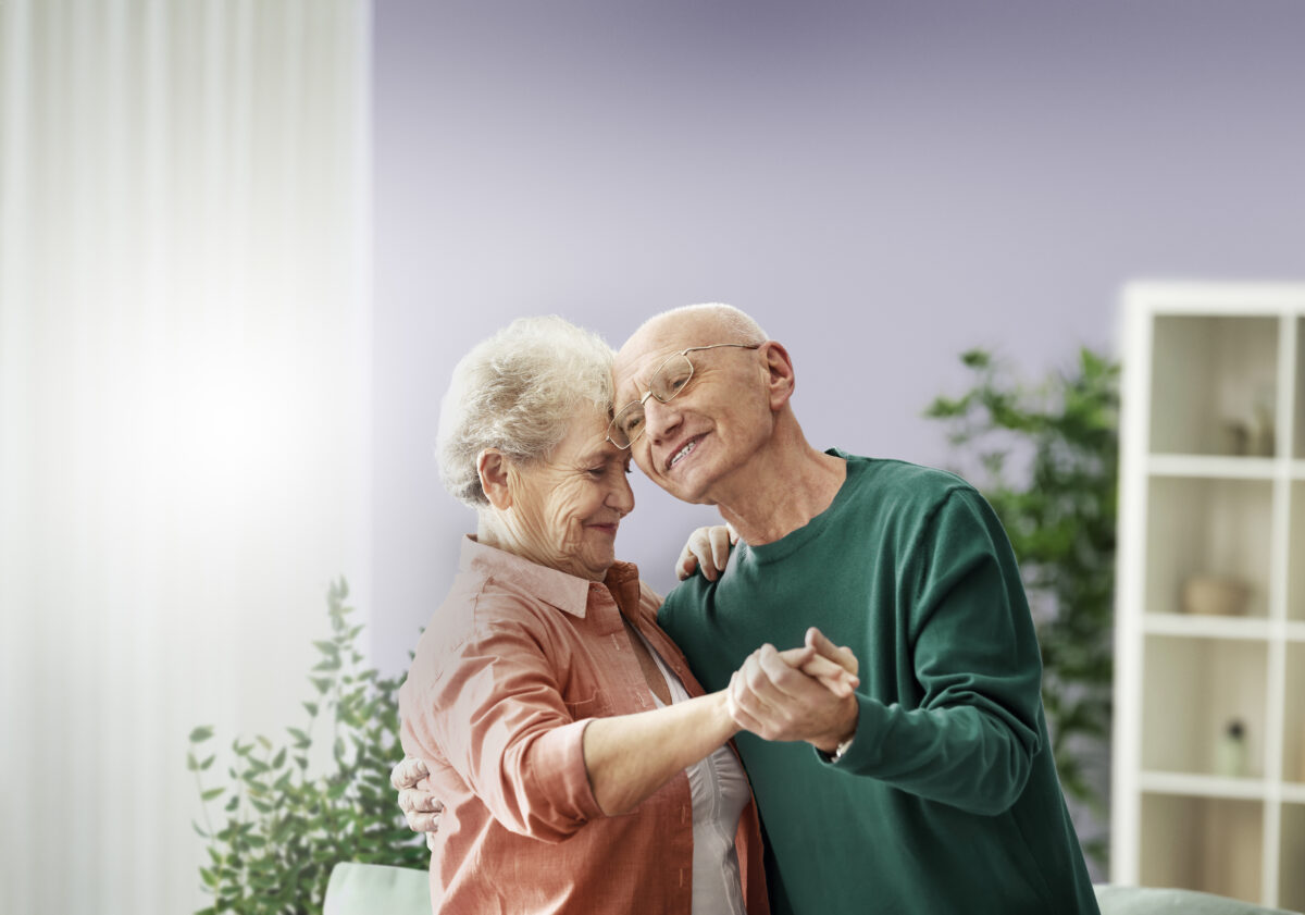 Cute elderly couple dancing at home