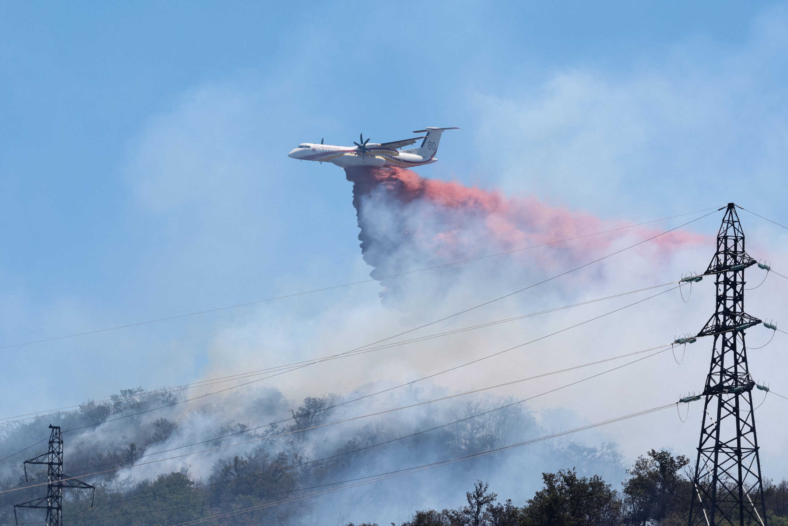 A firefighting plane drops fire retardant as it flies over a wildfire in Ille-sur-Tet near Perpignan, France, July 6, 2026. REUTERS/Alexandre Dimou