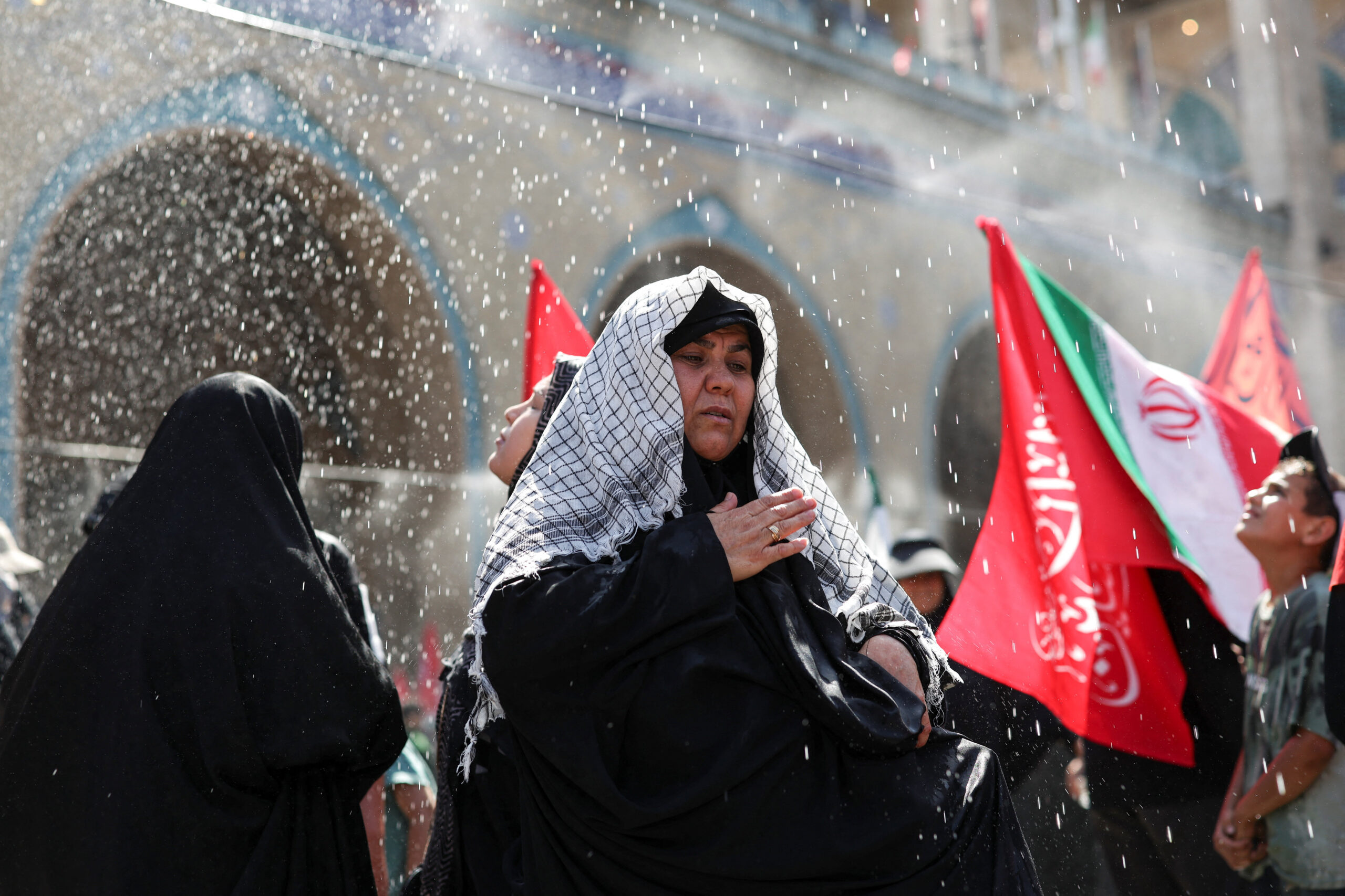 People cool themselves under sprayed water as they attend a public farewell ceremony to pay their respects to late Supreme Leader Ayatollah Ali Khamenei, who was killed on February 28 in Israeli and U.S. airstrikes, at the Imam Khomeini Grand Mosalla, in Tehran, Iran, July 5, 2026. REUTERS