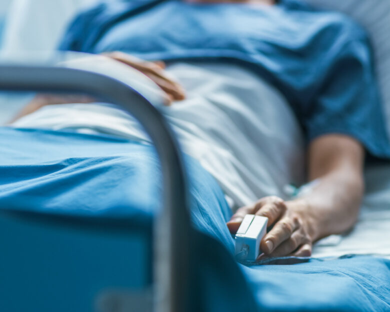 In the Hospital Sick Male Patient Sleeps on the Bed. Heart Rate Monitor Equipment is on His Finger.