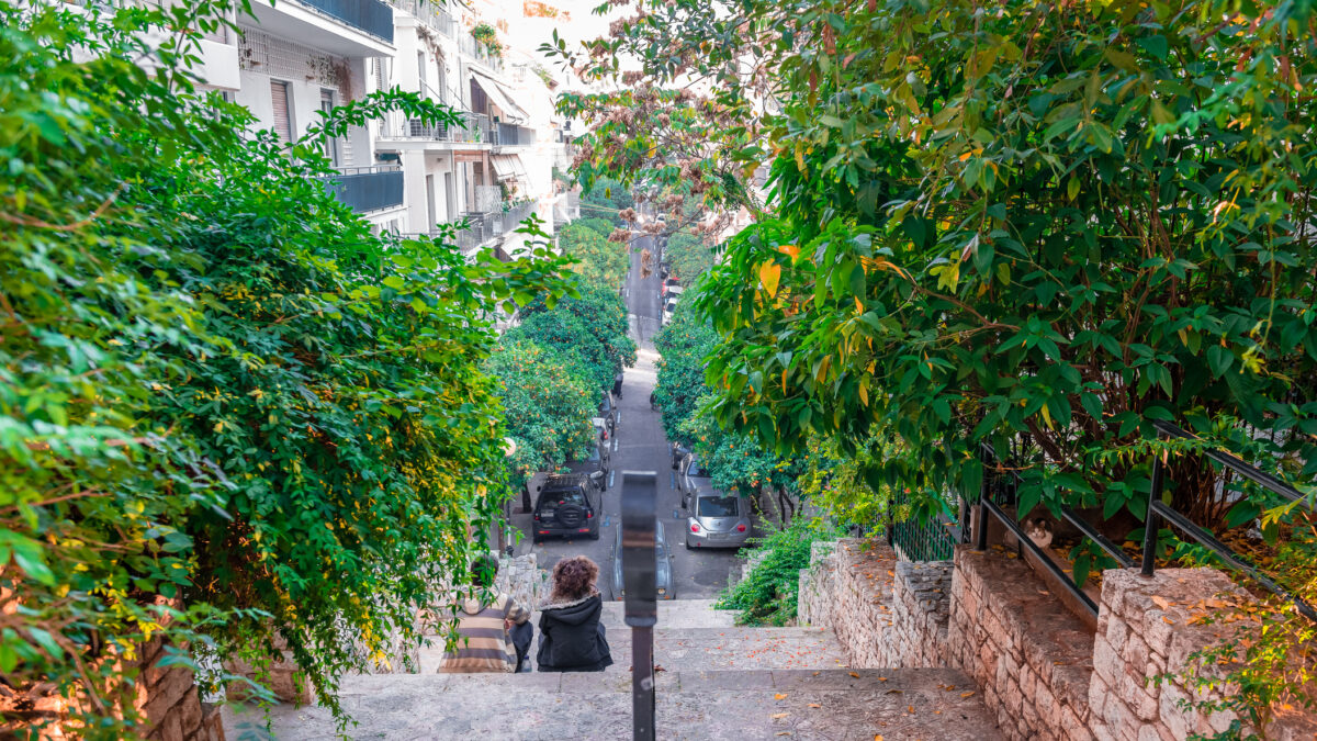 Rear view of a young boy and a young girl sitting side by side in the neighbourhood of Kolonaki, under mount Lycabettus