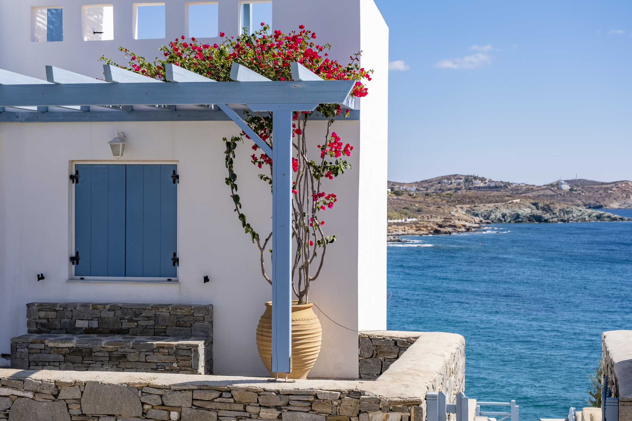Typical white homes with blue decoration in Greek architecture. Modern minimalist house exterior. Clear sky. Poster template background for real estate, tourism hotel and villa vacation rentals with large copy space.