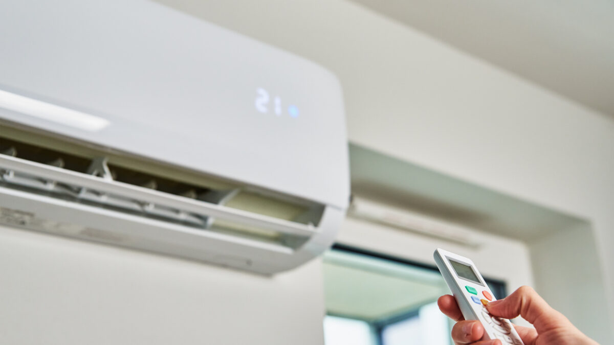 Hand adjusting temperature on air conditioner with remote control, Working air conditioner for comfort temperature in home at hot summer