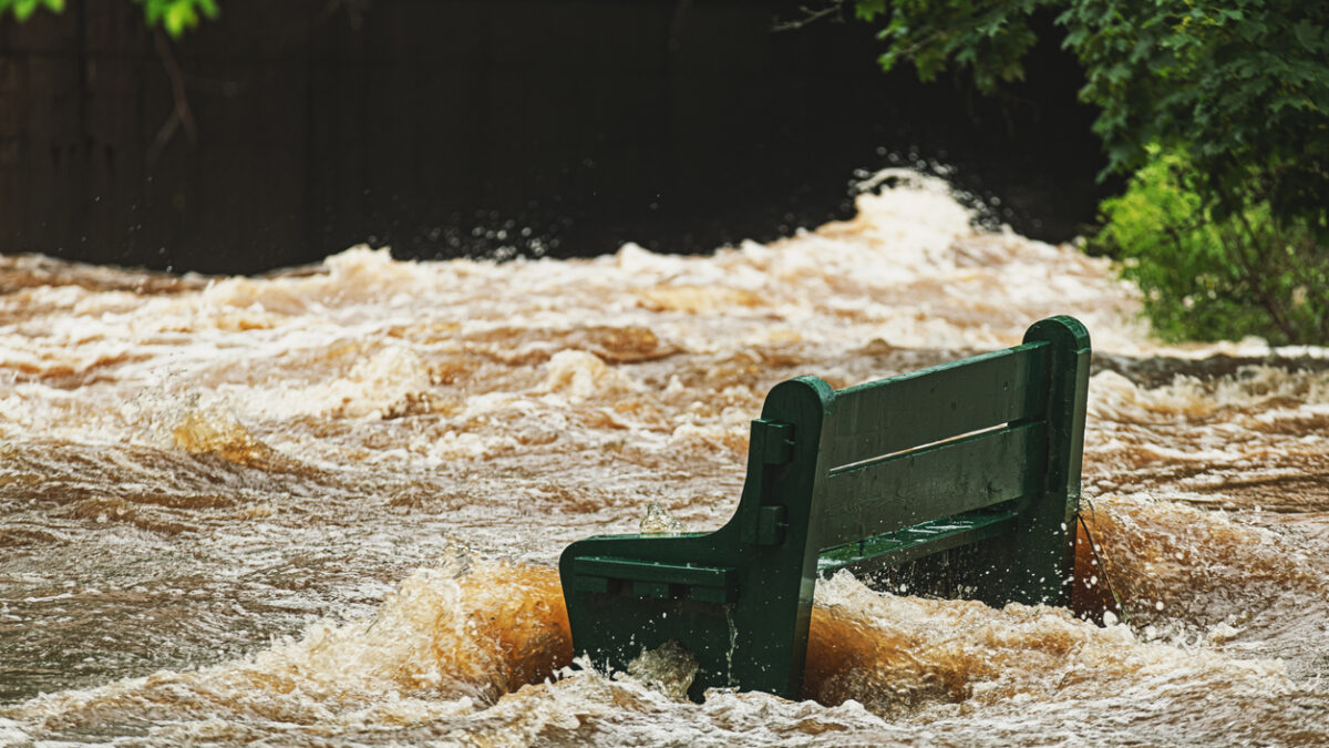 A park bench is overwhelmed by river flood water after record breaking rainfall.