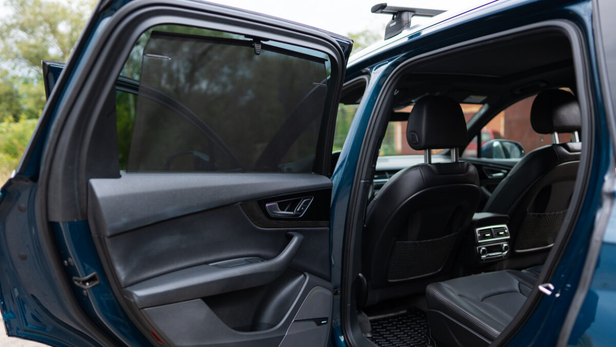 Rear passenger's door of luxury automobile being opened while vehicle being parked in urban area. Clear lines and stylish design of modern car. High quality photo