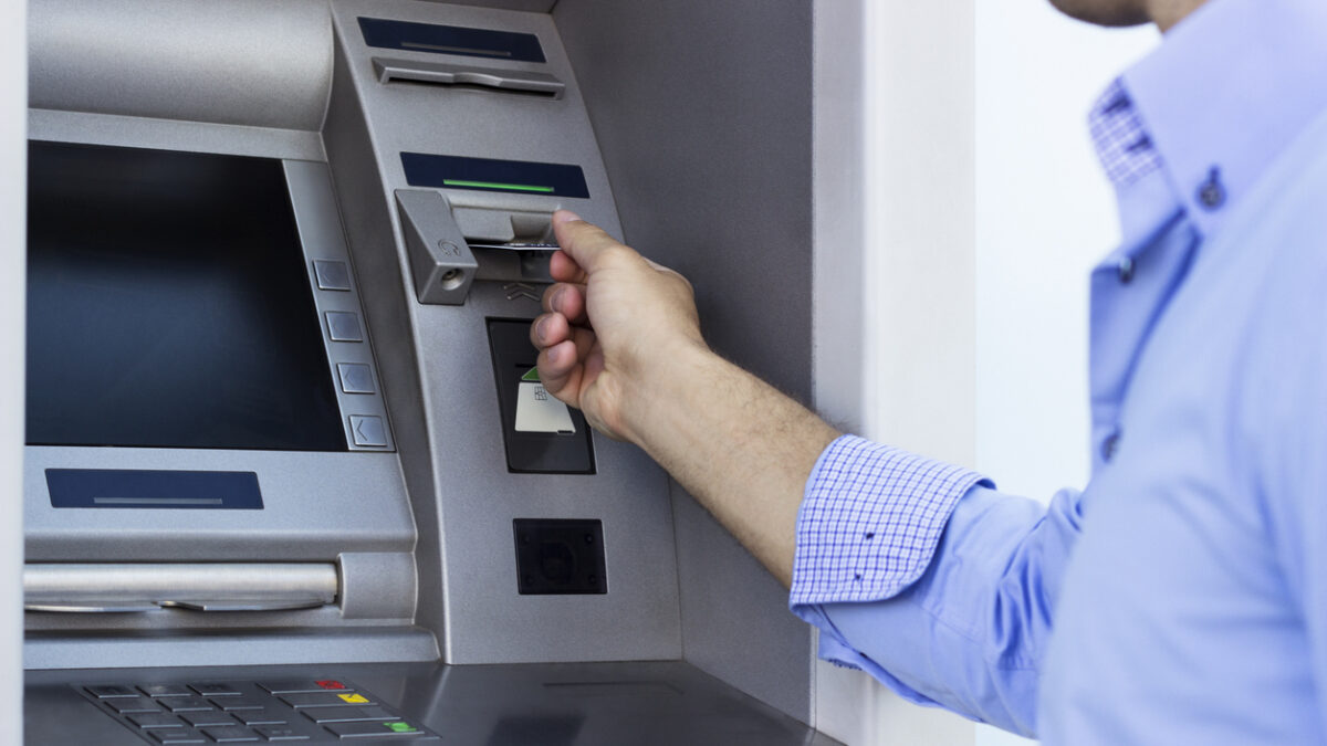 Hand of man with credit card, using a ATM