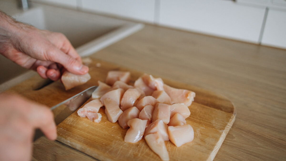 This culinary scene showcases a skilled chef in action, expertly slicing a chicken breast in the kitchen