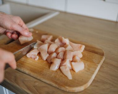 This culinary scene showcases a skilled chef in action, expertly slicing a chicken breast in the kitchen