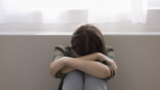Unhappy lonely adolescent girl suffers from bullying at school, hiding face, feels depressed, hopeless, offended, think about personal problem, worried about lack of communication. Teenage concerns