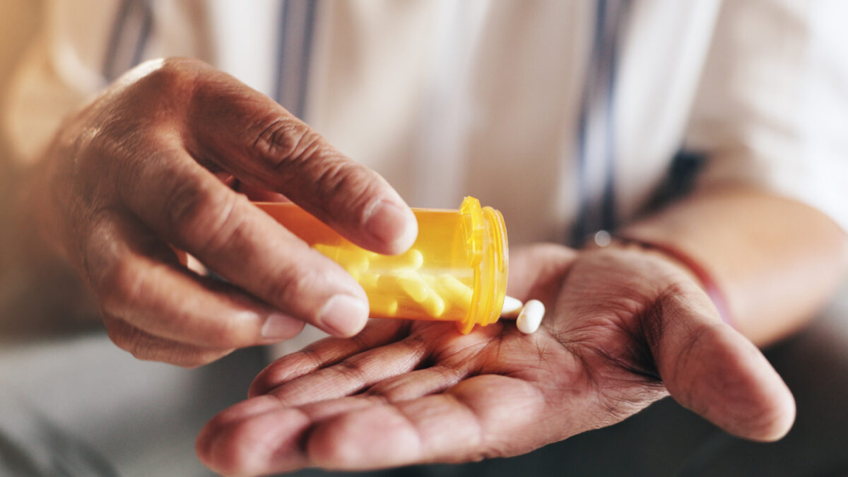Hands, pills and bottle in closeup for person with drugs, routine and schedule for health in home. Elderly patient, container and pharma product for supplements, wellness or benefits in retirement