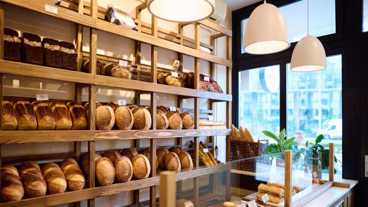 patisserie-Display of various types of freshly baked bread arranged on wooden shelves and inside a glass counter in a bakery shop, creating a warm and inviting atmosphere