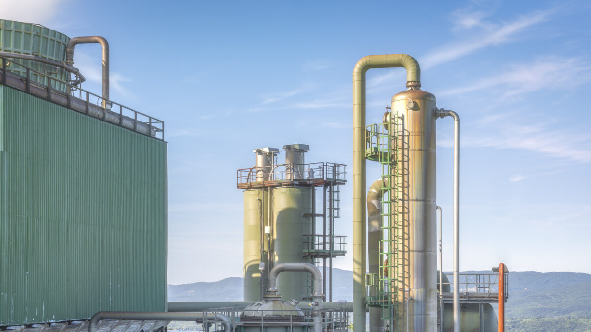Industrial landscape view of a Geothermal Complex in Larderello, Tuscany, the world's oldest geothermal energy production site. Large pipes, cooling towers and rolling hills.