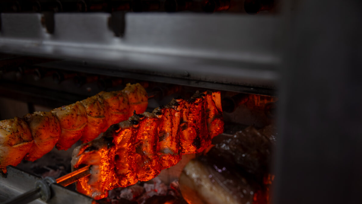 variety of meats on skewers cooking in a rotisserie