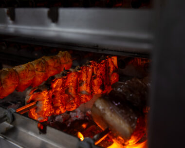 variety of meats on skewers cooking in a rotisserie