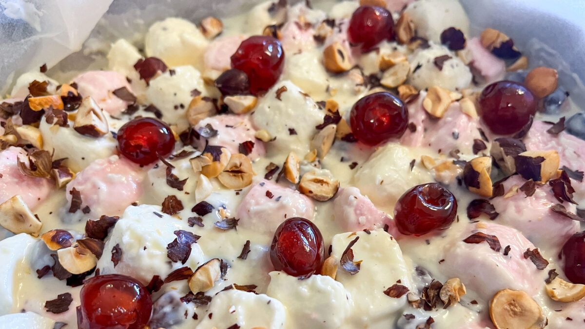 a homemade white chocolate rocky road mixture spread into a tray, finished with bright glacé cherries