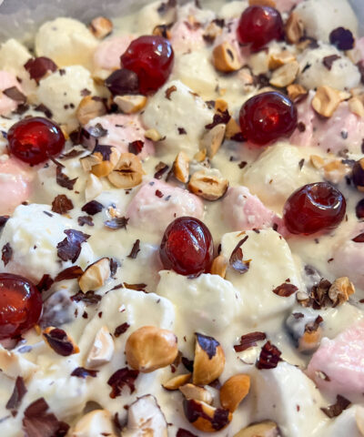 a homemade white chocolate rocky road mixture spread into a tray, finished with bright glacé cherries