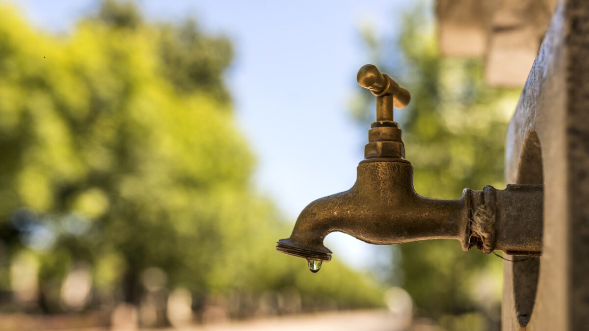 close up photo of Old and used Water faucet leaking with dripping drops during bright, hot sunny day- vrusi