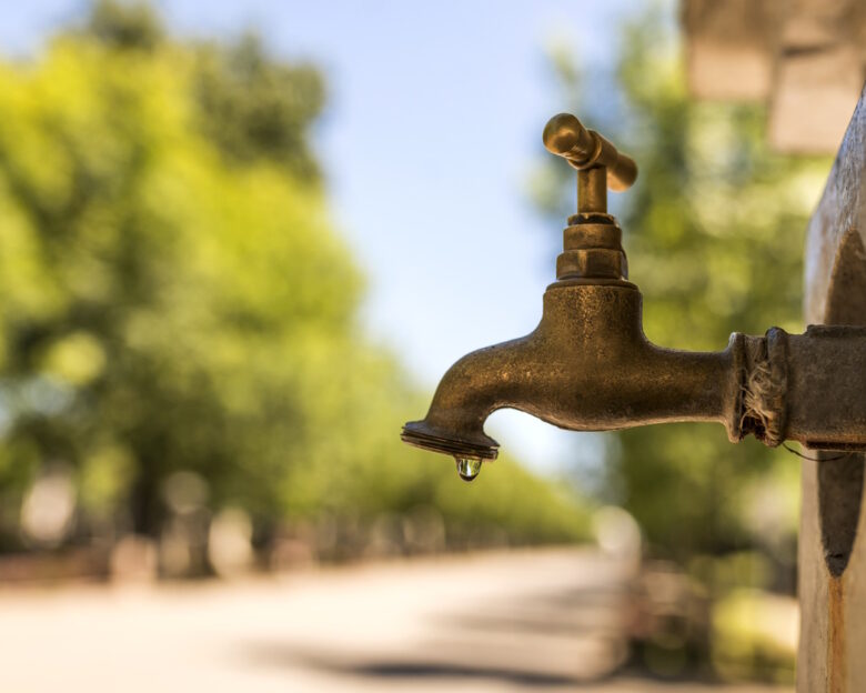 close up photo of Old and used Water faucet leaking with dripping drops during bright, hot sunny day- vrusi