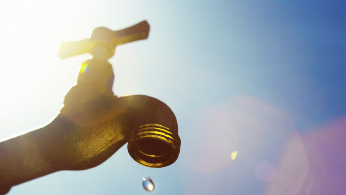 A single droplet falls from a faucet, symbolizing water scarcity or drought.