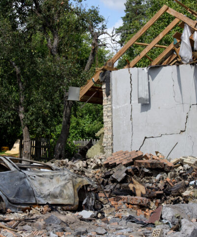 A crushed car is outside a house damaged by a missile strike, Kapitanivka village, Kyiv region, Ukraine, on July 29, 2026. On July 24, 2026, Russian forces launched ballistic missiles at a private training ground in Bucha district where a weapons exhibition was taking place. The missiles also struck a nearby residential area, damaging private houses and cars. Twelve people were killed, and around 100 were injured in the attack. (Photo by Marianna Kotyk/Ukrinform/NurPhoto)NO USE FRANCE