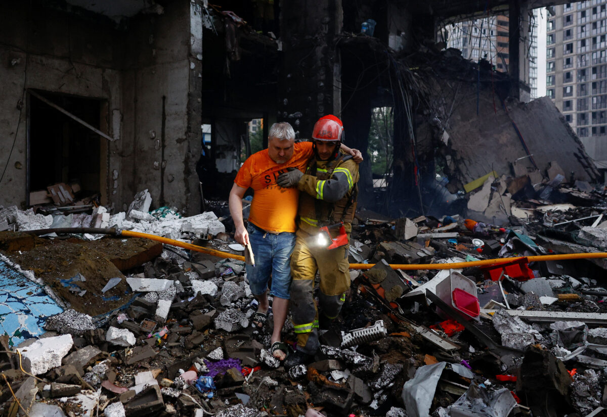 A rescuer assists a man at the site of an apartment building, which was heavily damaged during Russian missile and drone strikes, amid Russia's attack on Ukraine, in Kyiv, Ukraine, July 6, 2026. REUTERS