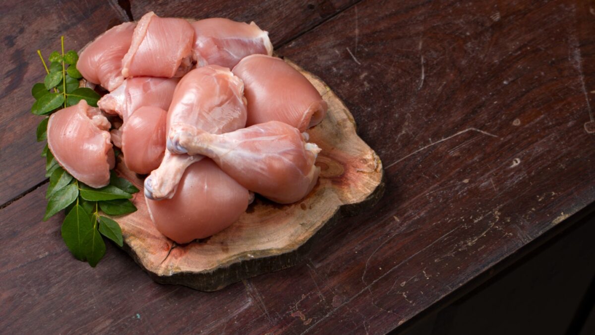 Raw chicken cuts or parts like breast fillet,chicken stripes; Raw chicken cuts or parts like breast fillet,chicken stripes; chicken legs without skin arranged on a sliced wooden log base and garnished with curry leaves and placed on wooden background