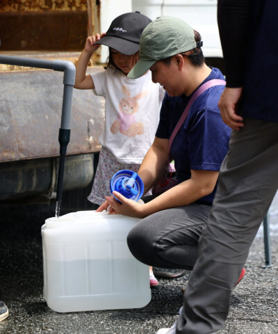 Yuka Shimada (45) and her daughter Tsugumi (3) receive water aid due to a water supply outage caused by an earthquake with a magnitude of 7.1 struck Japan's southern Kumamoto prefecture, at a community center in Yatsushiro, Japan, July 30, 2026. REUTERS/Issei Kato